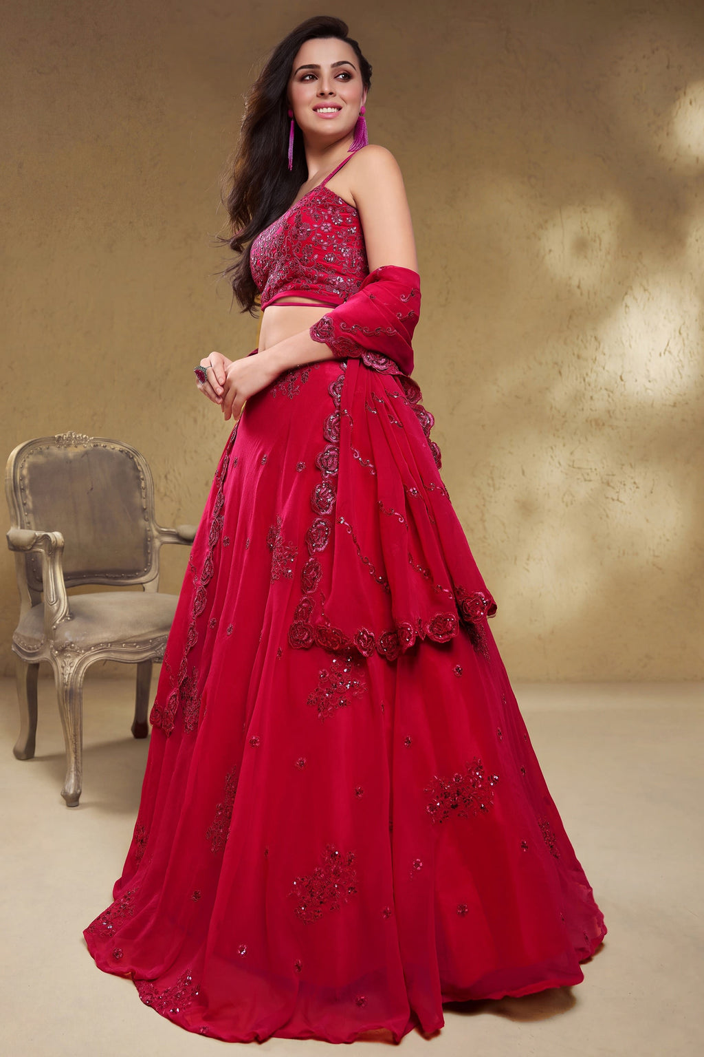 Full-length side view of a reddish pink engagement dresses for women lehenga in georgette with zari, dori and sequin work on the skirt.