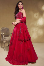 Full-length side view of a reddish pink engagement dresses for women lehenga in georgette with zari, dori and sequin work on the skirt.
