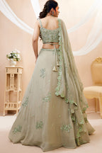 Full-length back view of a pista green mehndi outfits lehenga in georgette with an open back blouse with dori tie and zari and sequin work.