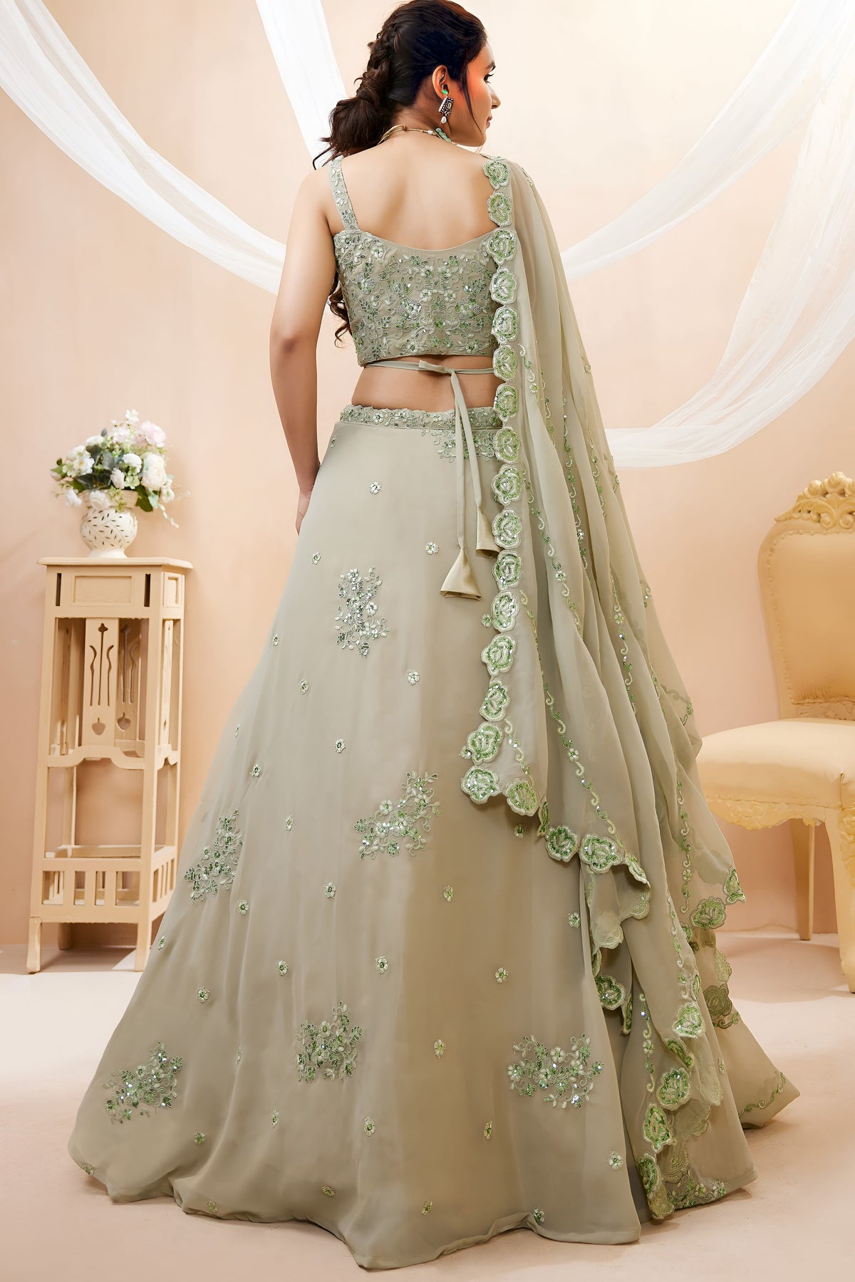 Full-length back view of a pista green mehndi outfits lehenga in georgette with an open back blouse with dori tie and zari and sequin work.