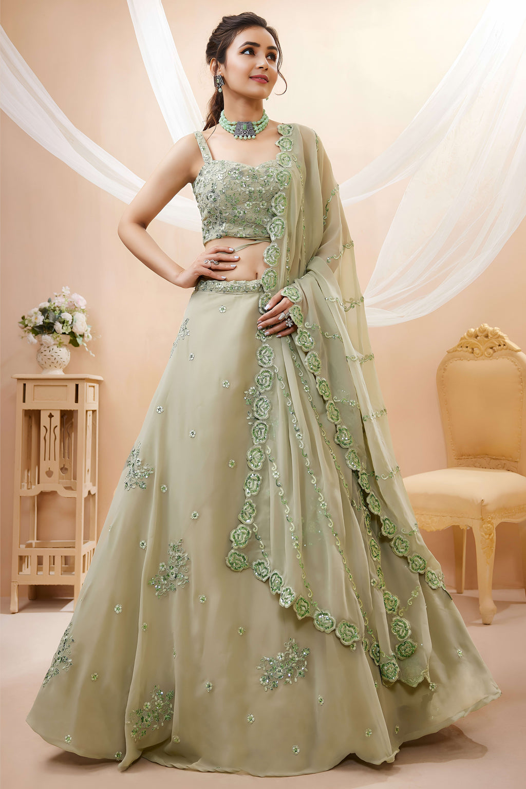 Woman wearing a pista green mehndi outfits lehenga in georgette with zari, dori and sequin work, sleeveless blouse, full-length front view.