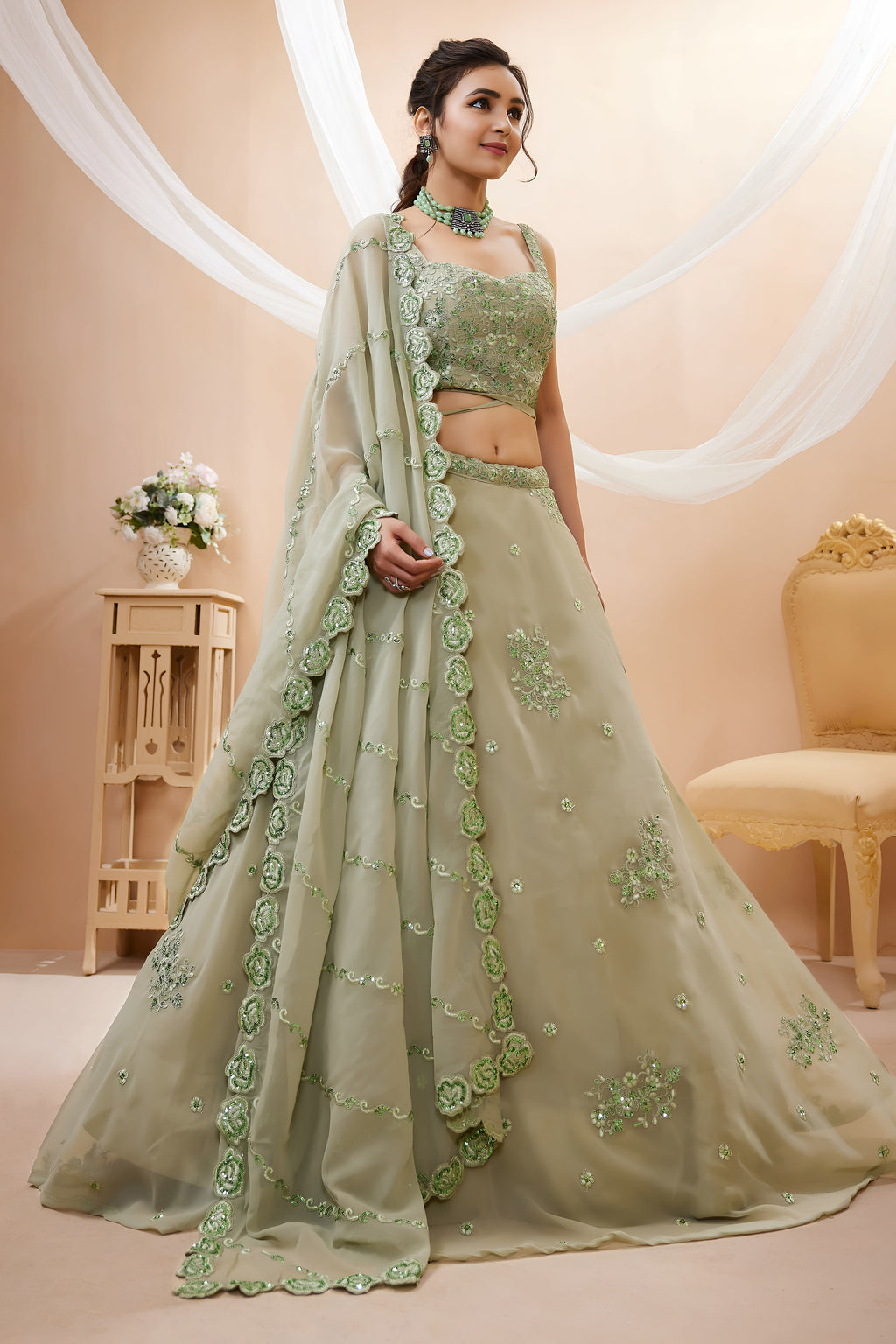 Full-length side view of a pista green sangeet lehenga in georgette with zari, dori and sequin work on the flared lehenga skirt.