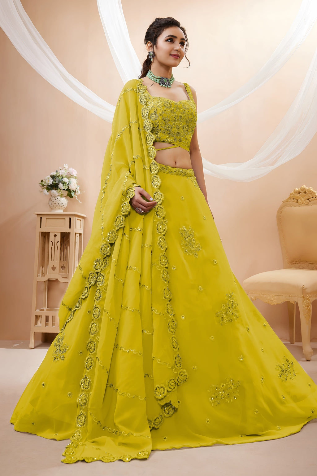Full-length side view of a bright yellow reception lehenga in georgette with zari, dori and sequin work on the flared lehenga skirt.