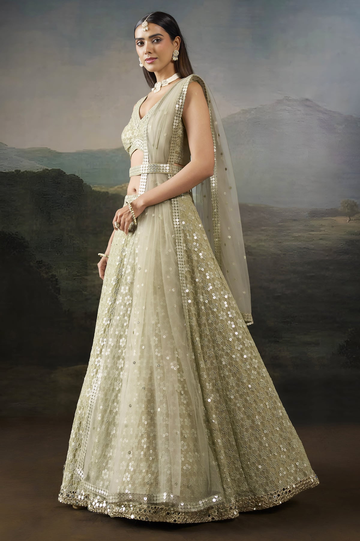 Side view of the champagne sequin lehenga showing the flared georgette skirt, worked border and net dupatta draped behind.