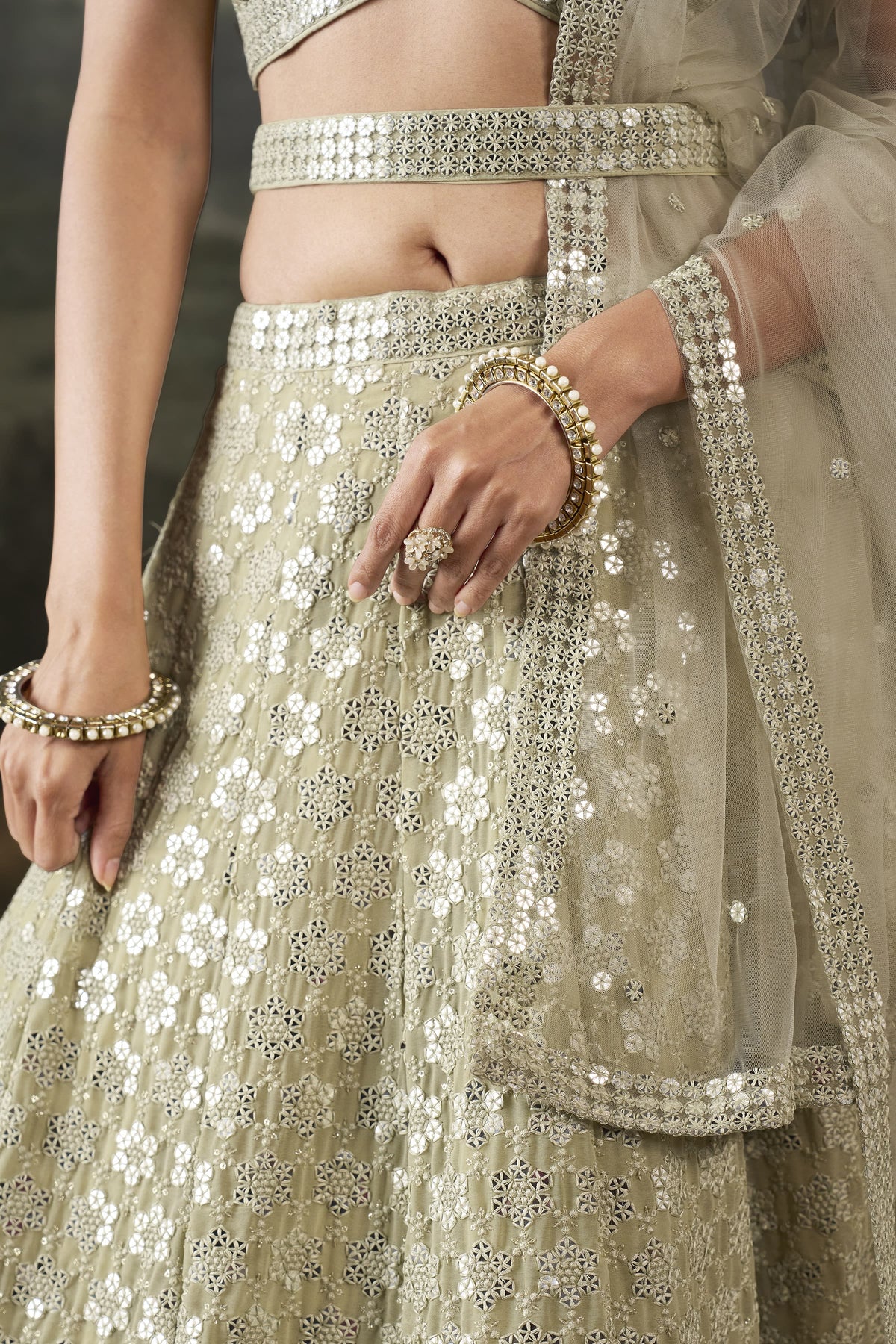 Waist-down close-up of the champagne mehendi lehenga showing the sequinned georgette skirt, worked belt and net dupatta border.