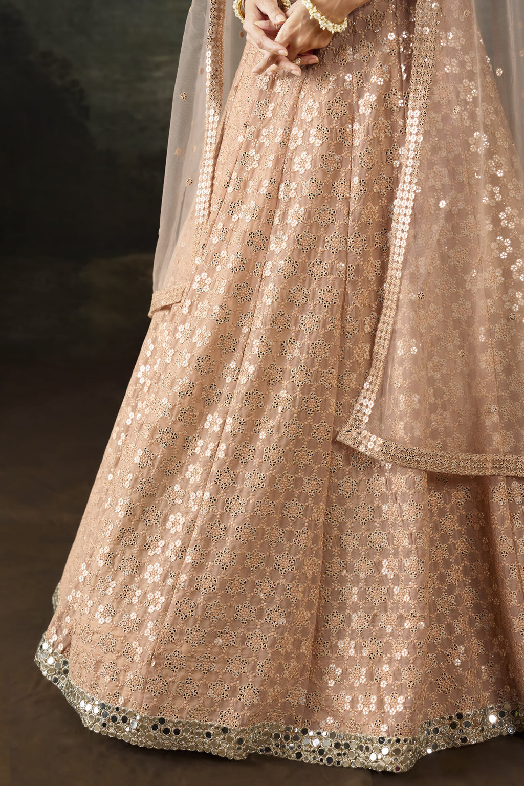 Close-up of the pale peach lehenga skirt, a shimmering sangeet outfits for women piece with dense sequin work and a net dupatta edge.