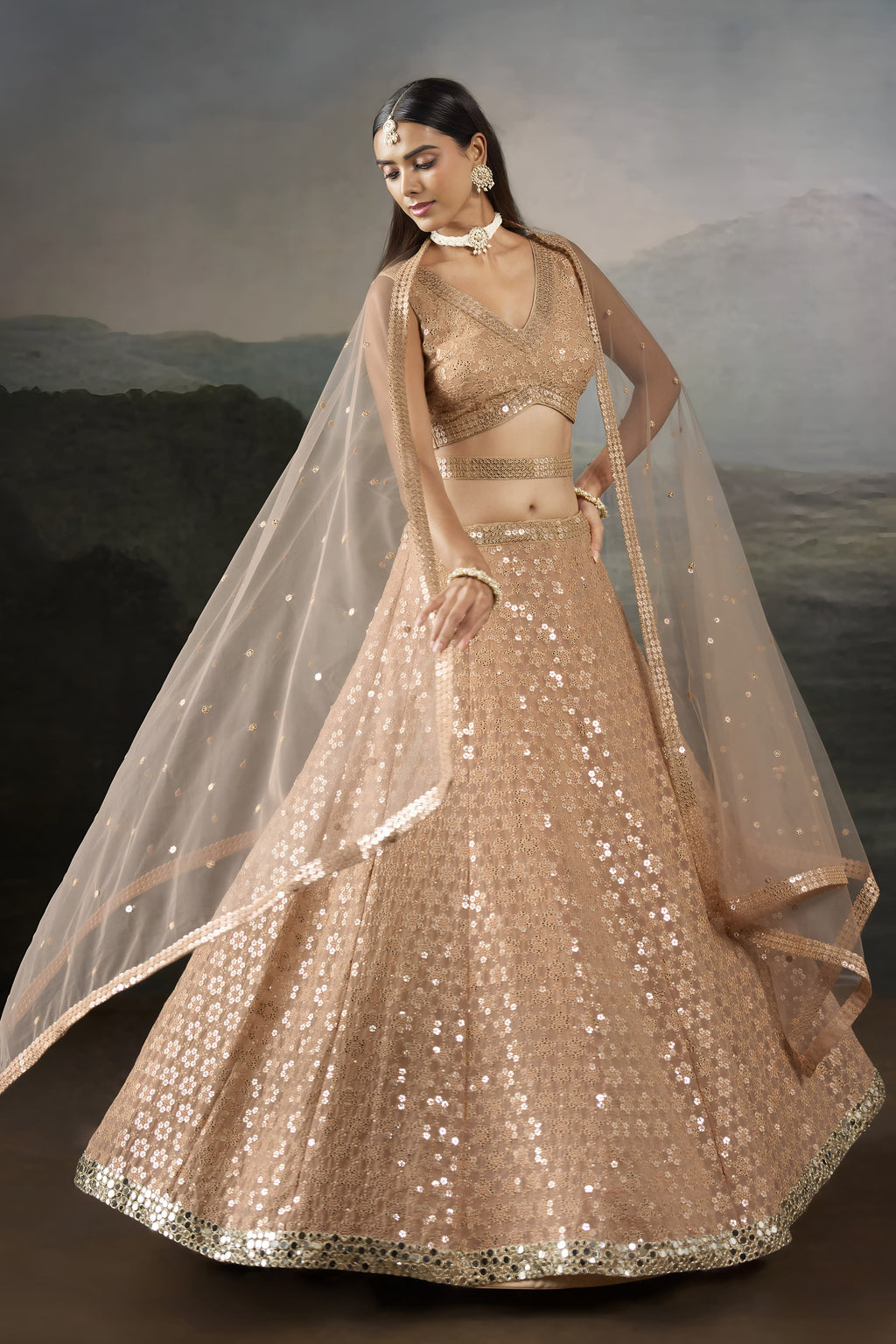 Front pose of the pale peach lehenga, a bright sangeet outfits for women choice, with a V neck blouse and flared sequinned skirt.