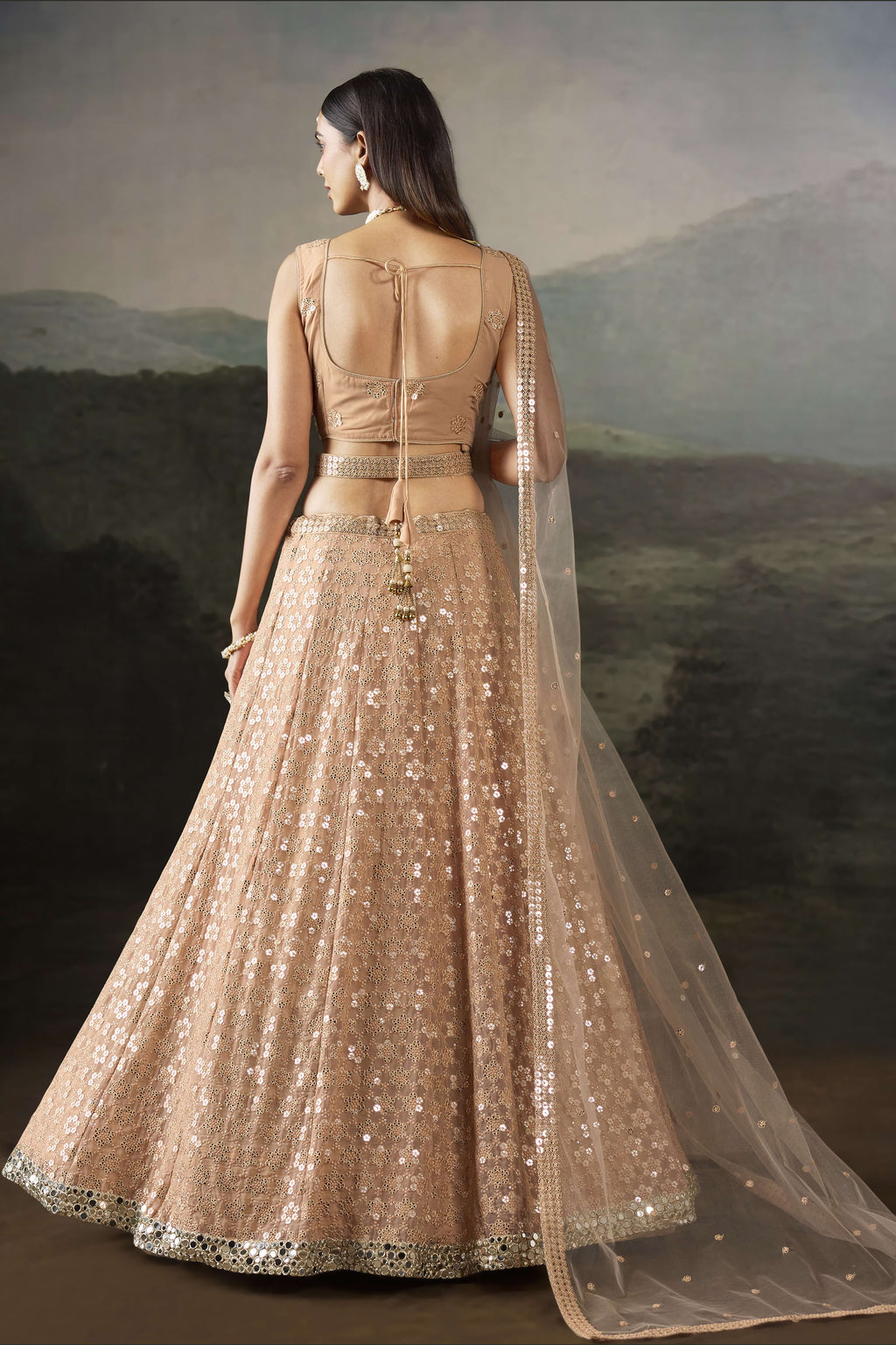 Back view of the pale peach lehenga, a graceful sangeet outfits for women option, with a tie-up back blouse and flowing net dupatta.