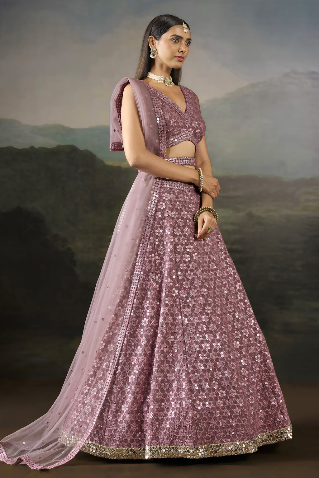 Front pose of the baby pink wedding wear lehenga choli with a V neck blouse, flared sequinned skirt and sheer net dupatta.