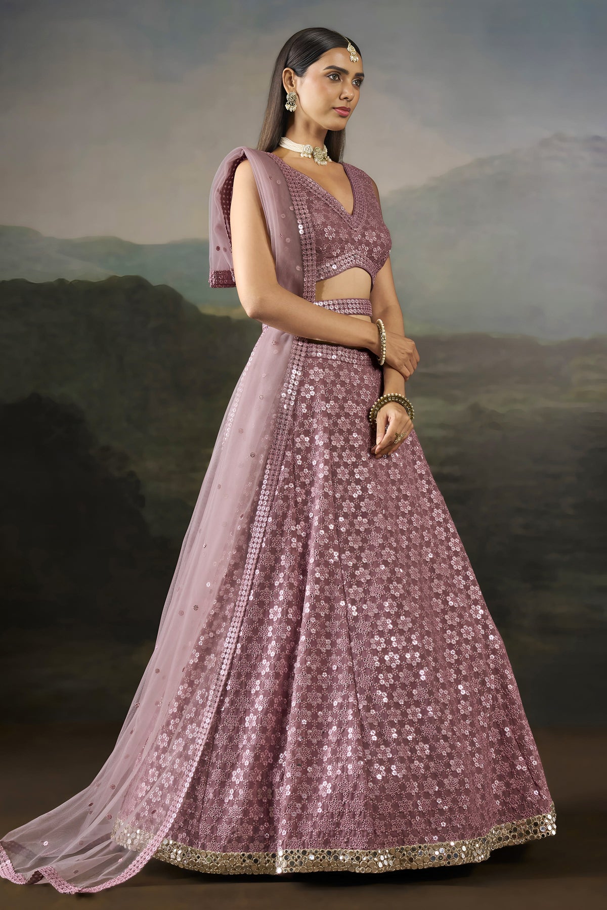 Front pose of the baby pink wedding wear lehenga choli with a V neck blouse, flared sequinned skirt and sheer net dupatta.