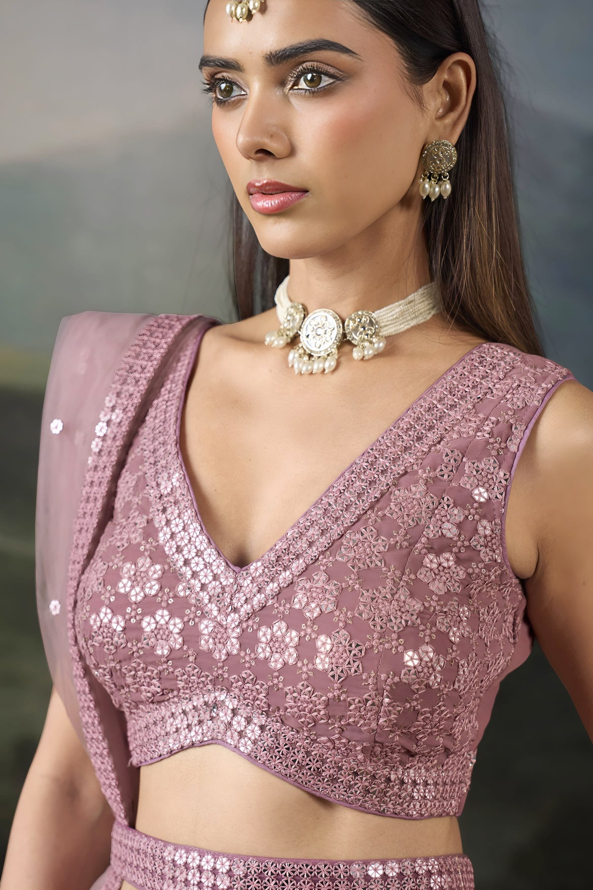 Close-up of the baby pink sangeet attire blouse with a deep V neckline, sequin and mirror work and a worked waist belt detail.