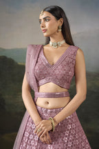 Half view of the baby pink wedding wear lehenga choli showing the V neck blouse, mirror work and sheer net dupatta over one shoulder.