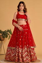 Woman wearing a red lehenga for wedding with zari and sequin embroidery, sleeveless round neck choli, full-length front view.