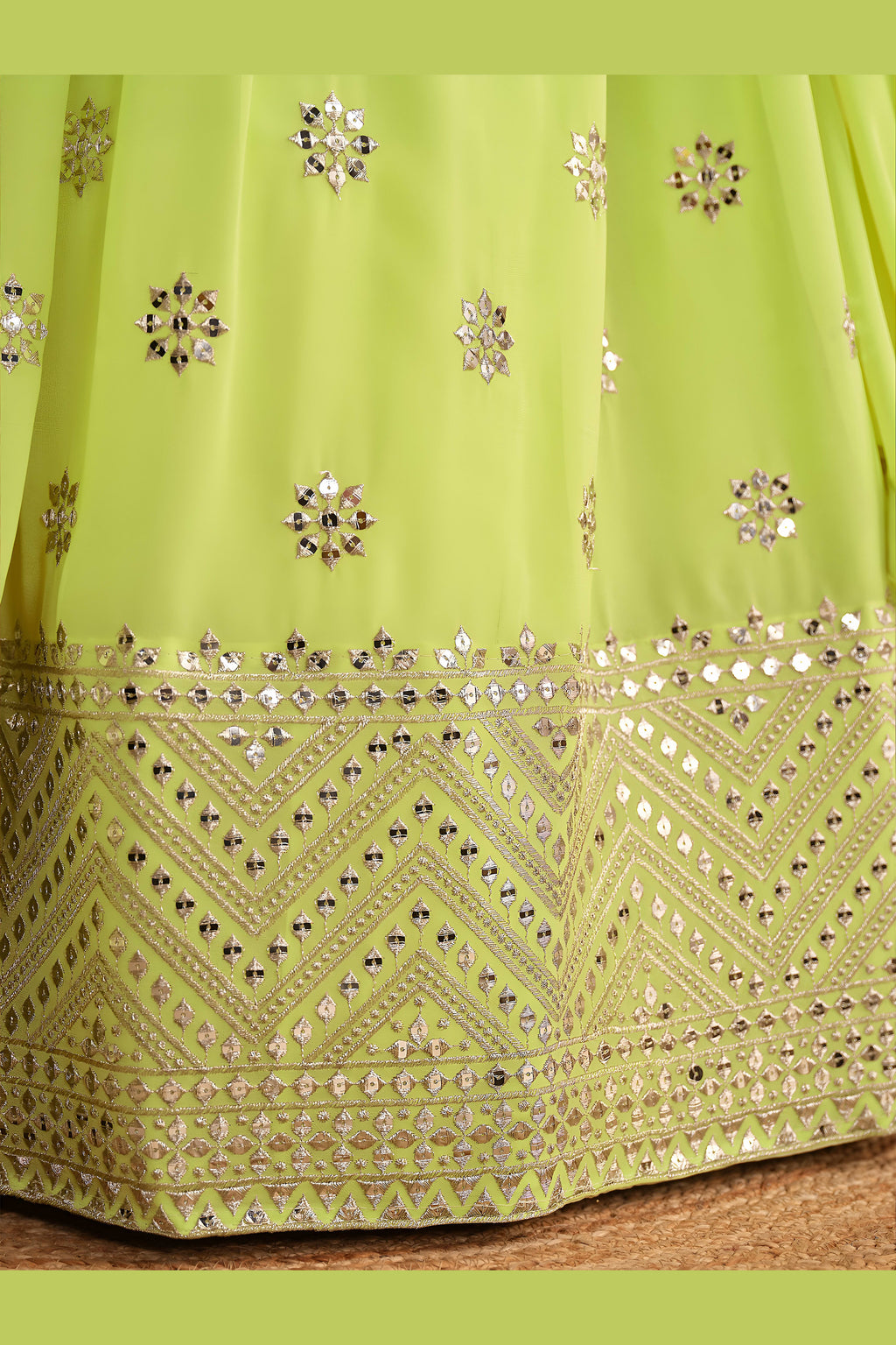 Detail view of a neon yellow sangeet lehenga showing intricate zari and sequin embroidery throughout on the lehenga skirt border.