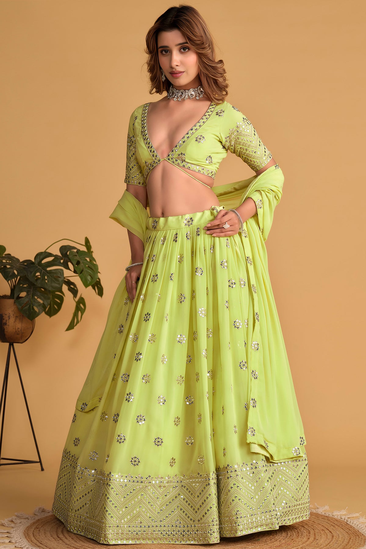 Full-length side view of a neon yellow party wear lehenga with zari and sequin embroidery throughout on the flared lehenga skirt.