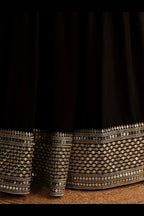 Detail view of a black party wear lehenga showing intricate zari and sequin embroidery throughout on the lehenga skirt border.