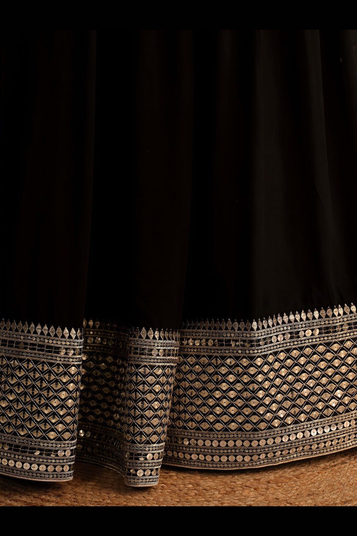 Detail view of a black party wear lehenga showing intricate zari and sequin embroidery throughout on the lehenga skirt border.
