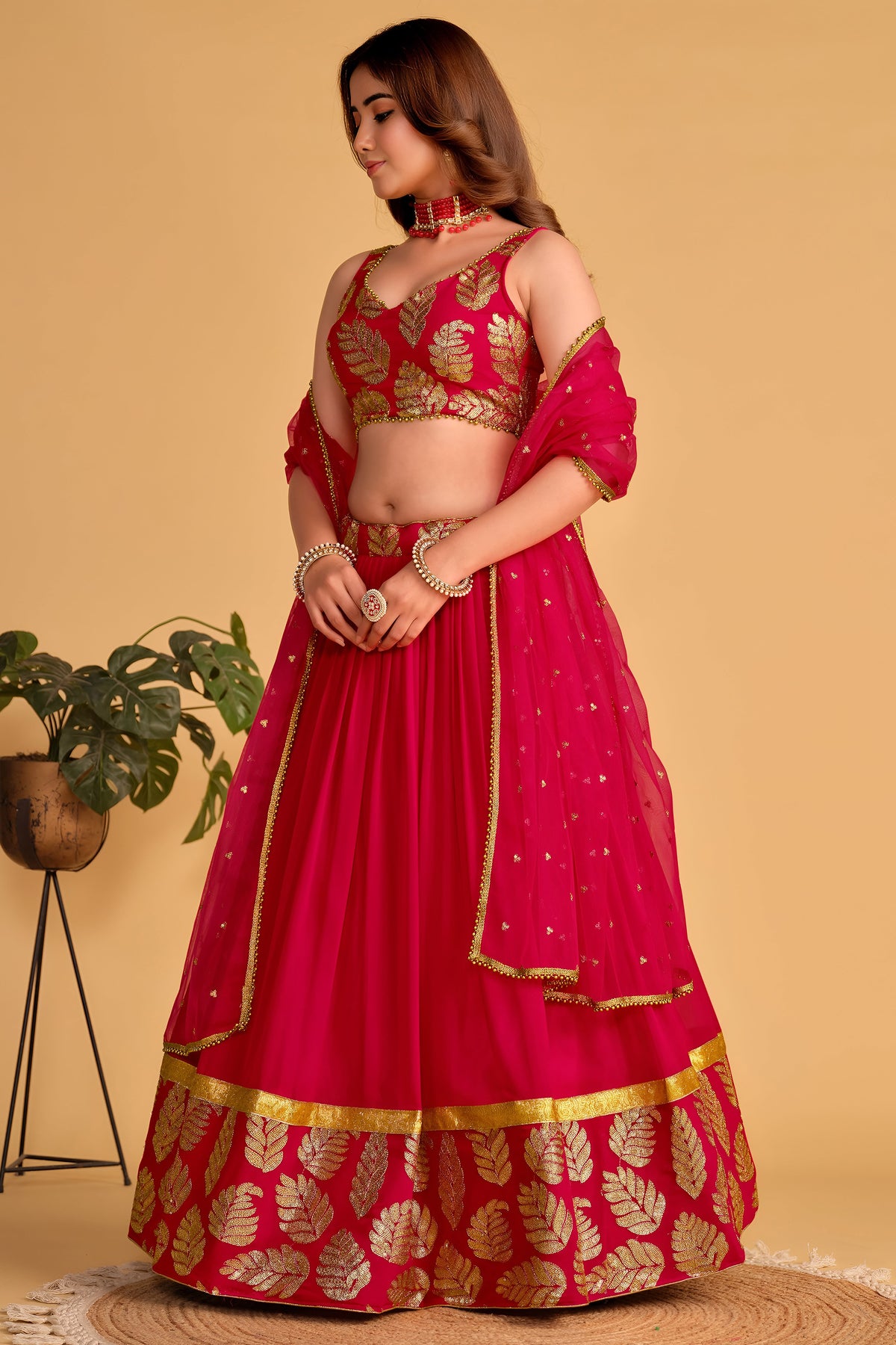 Alternate full-length view of a reddish pink engagement lehenga with zari and sequin embroidery on the sleeveless choli and lehenga.