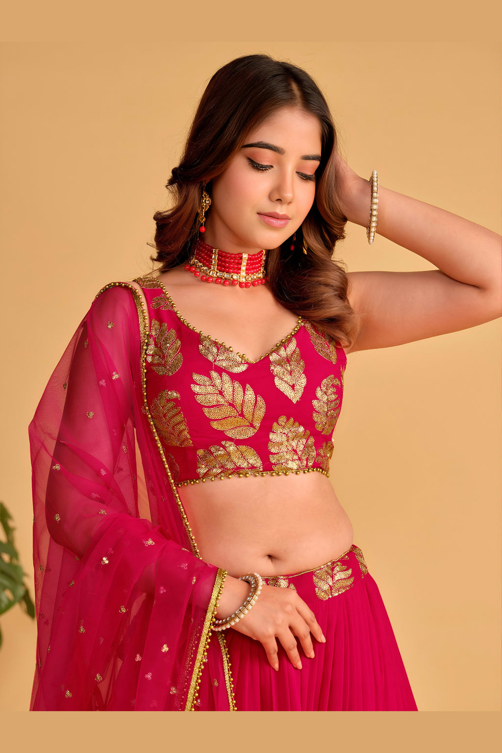 Detail view of a reddish pink engagement dresses for women lehenga showing intricate zari and sequin embroidery on the skirt border.