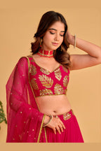 Detail view of a reddish pink engagement dresses for women lehenga showing intricate zari and sequin embroidery on the skirt border.