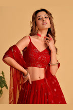 Close-up view of a reddish pink lehenga for wedding with detailed zari and sequin embroidery work on the sleeveless choli.