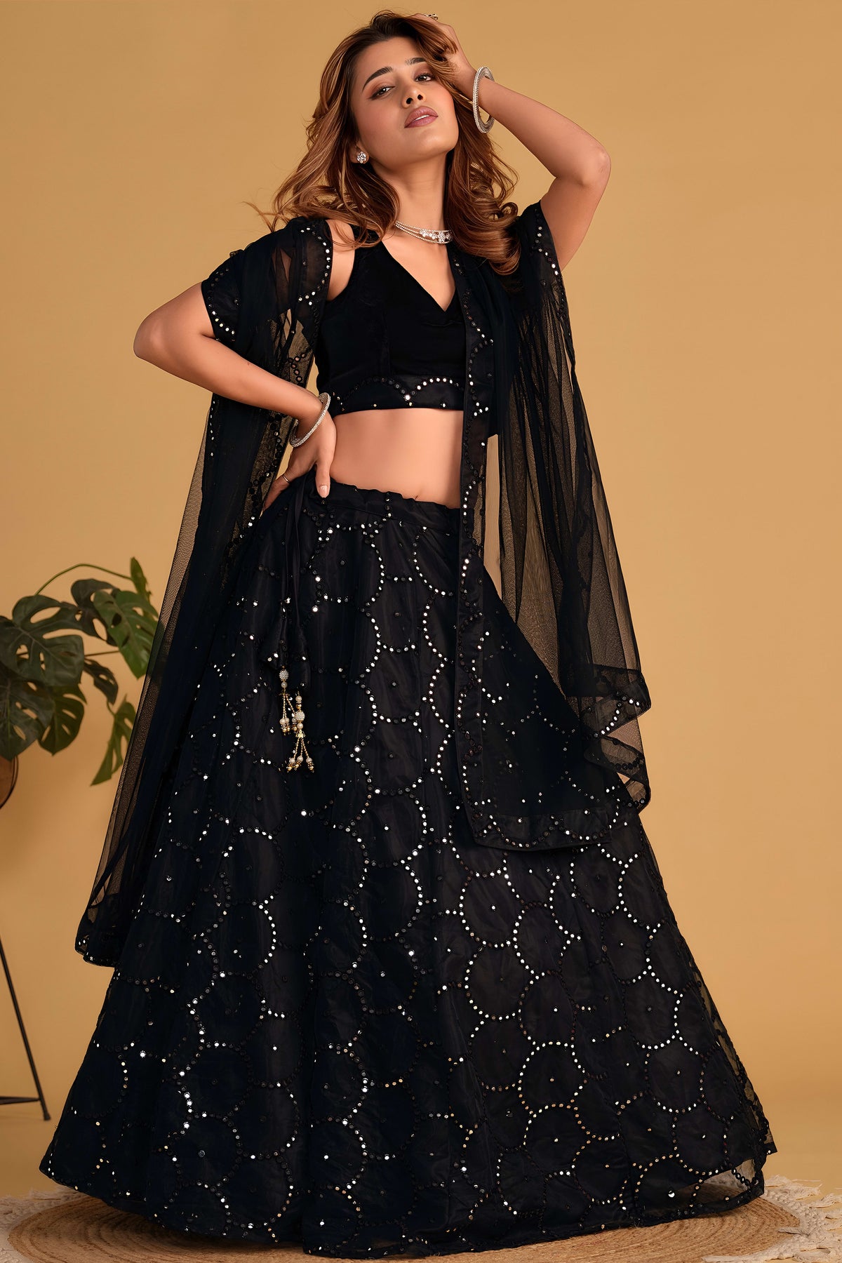 Full-length back view of a black cocktail lehenga with V neckline back velvet choli and zari and sequin embroidery work.