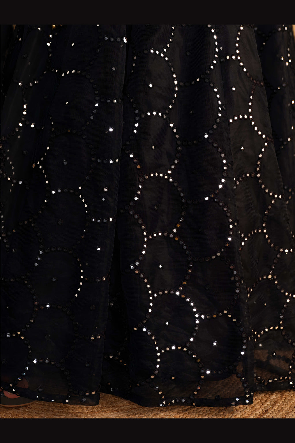 Detail view of a black party wear lehenga showing intricate zari and sequin embroidery on the organza lehenga skirt border.