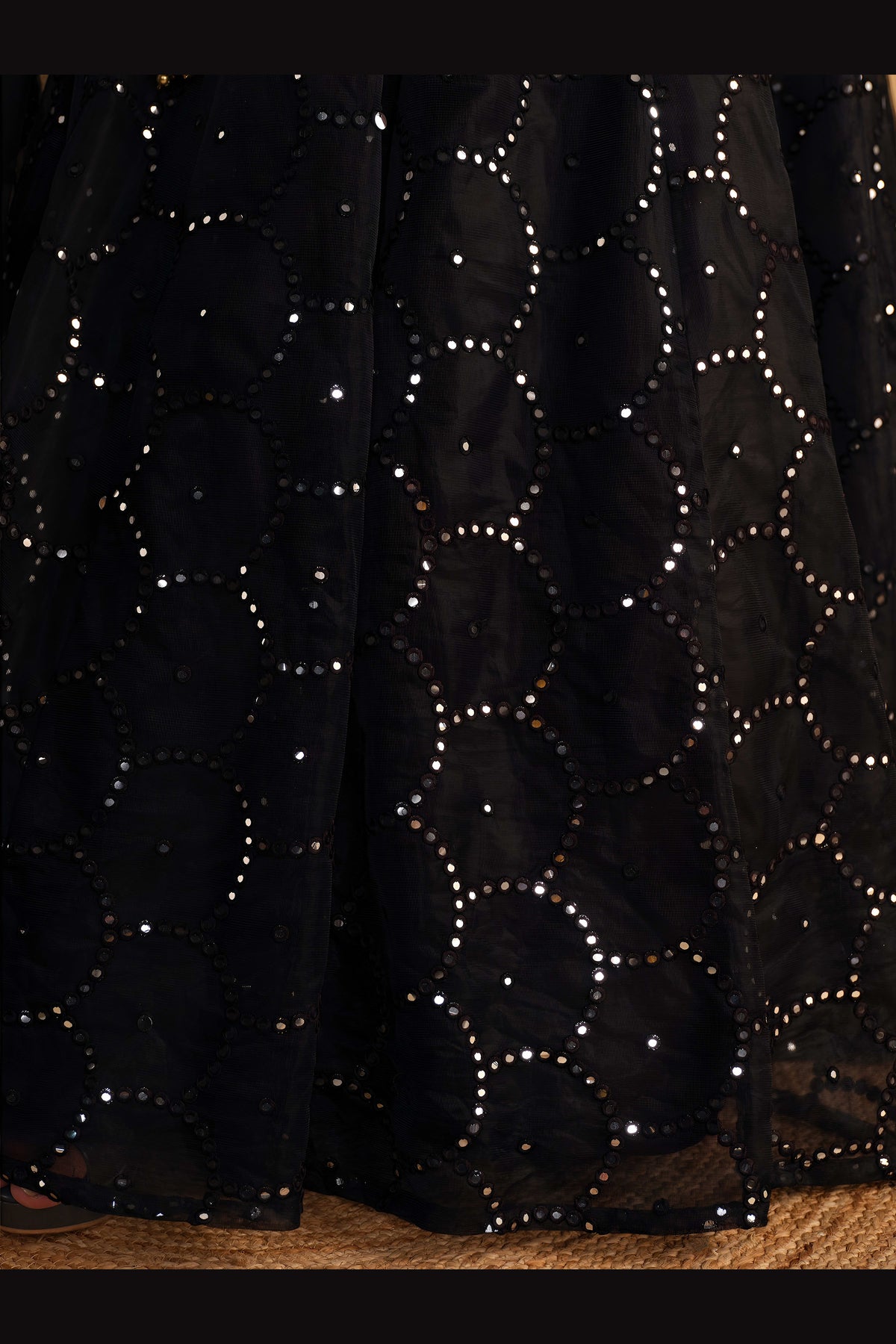 Detail view of a black party wear lehenga showing intricate zari and sequin embroidery on the organza lehenga skirt border.