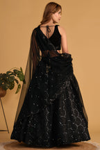 Full-length side view of a black cocktail lehenga with zari and sequin embroidery throughout on the flared organza lehenga skirt.