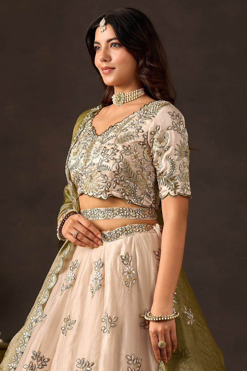 Light beige lehenga choli for sangeet flat lay, blouse back with round neckline embroidery.