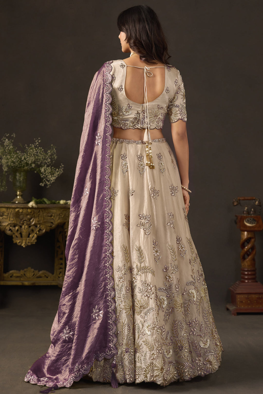 Light beige wedding guest lehenga choli, three-quarter front view, V neck blouse with zari work.
