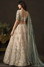 Light beige engagement lehenga choli, three-quarter front view, showing V neckline blouse with zari work.