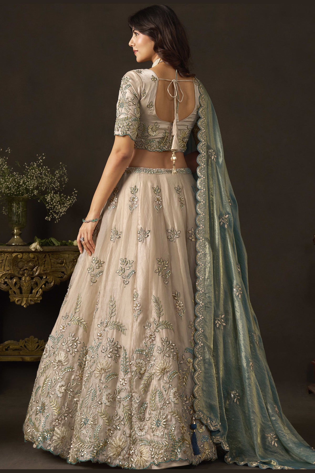 Light beige engagement lehenga choli, three-quarter front view, showing V neckline blouse with zari work.