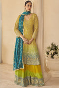 Woman wearing a yellow outfit for turmeric wedding ceremony embroidered traditional outfit with a blue dupatta