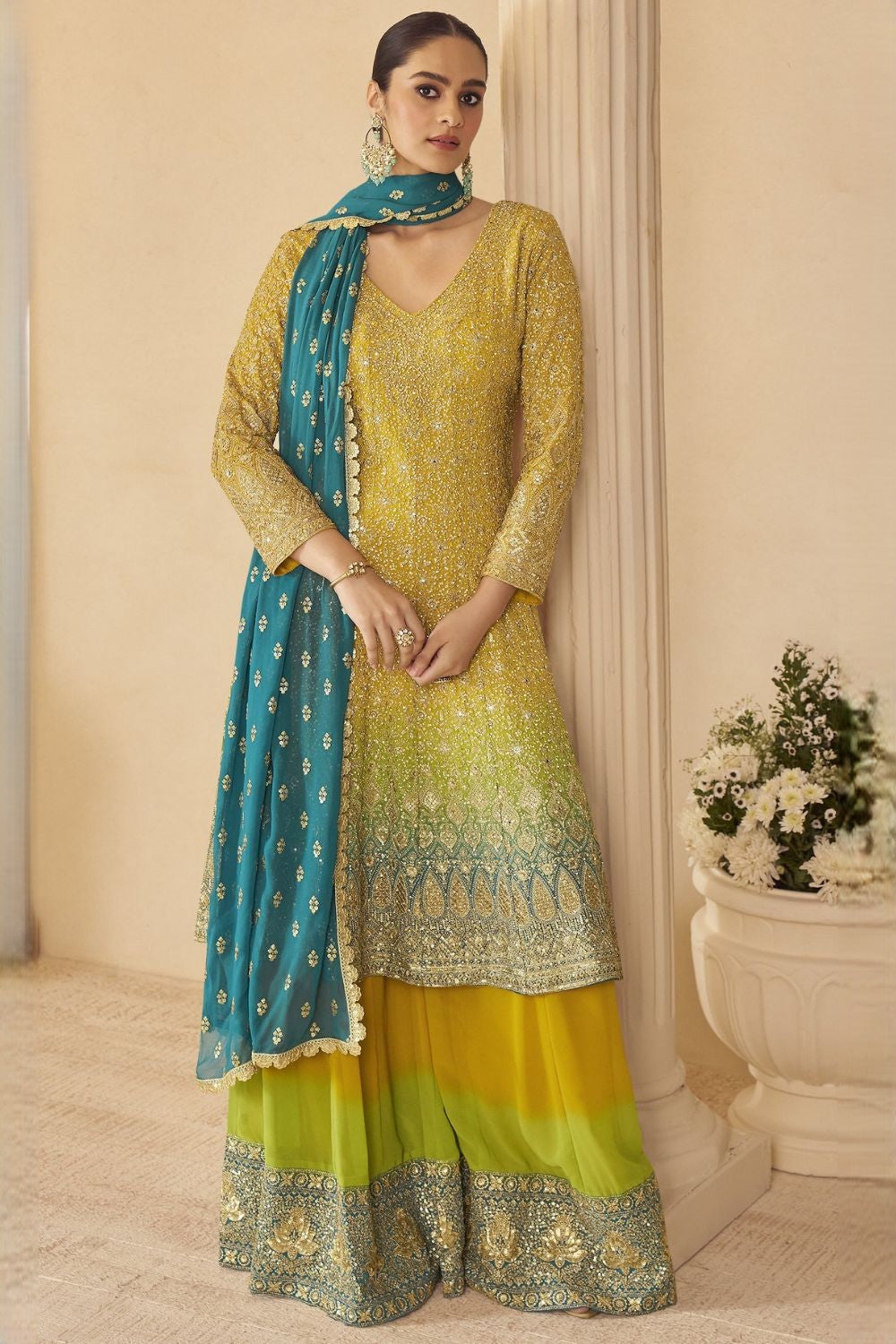 Woman wearing a yellow outfit for turmeric wedding ceremony embroidered traditional outfit with a blue dupatta