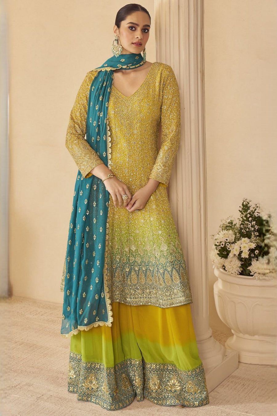 Woman wearing a yellow outfit for turmeric wedding ceremony embroidered traditional outfit with a blue dupatta